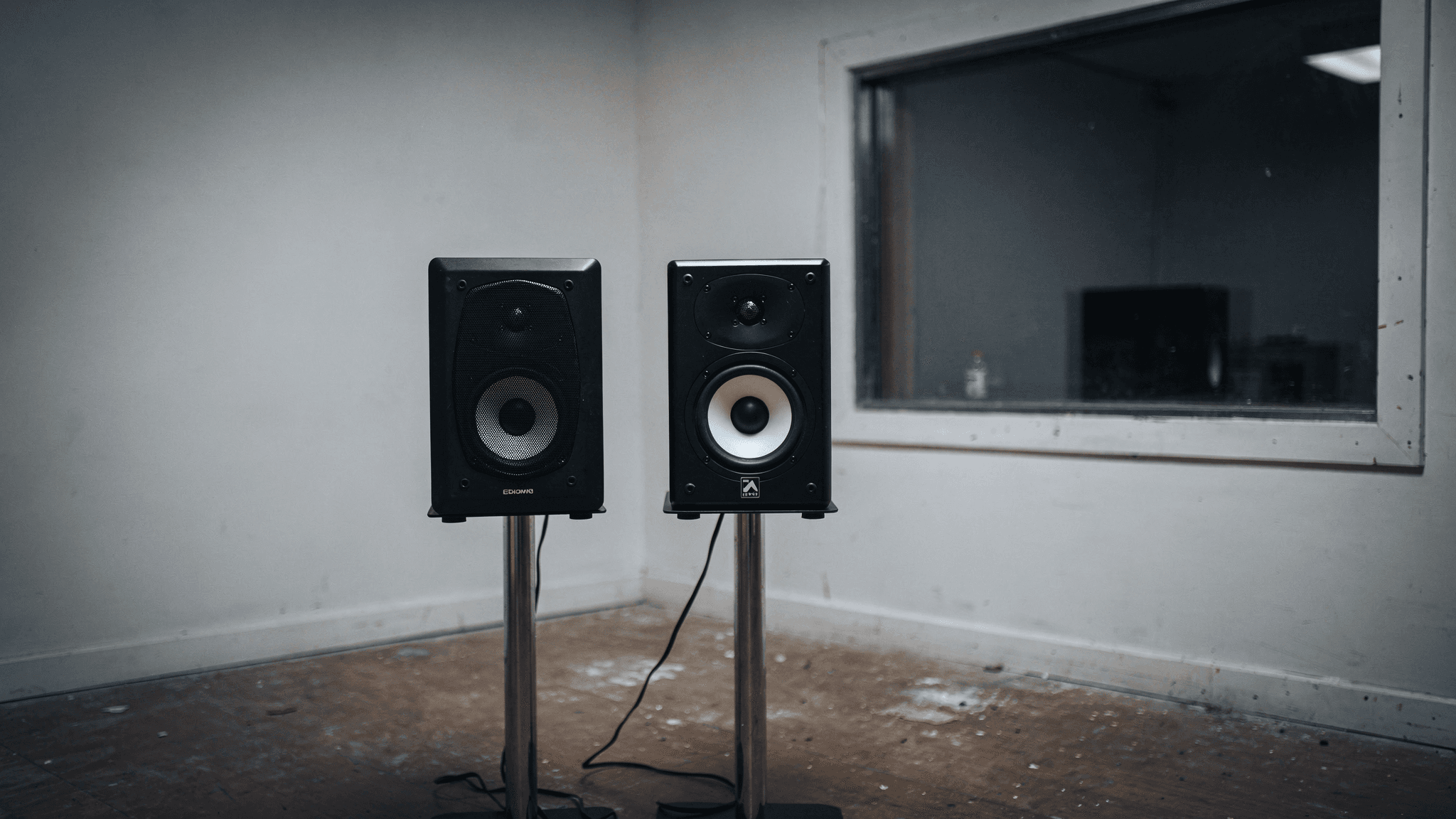 Premium studio monitors on stands in a bare, untreated room. Image generated with Artlist.